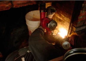 Chipping hammer being used in fireplace to make room for liner to fit thru to connect directly onto wood stove insert